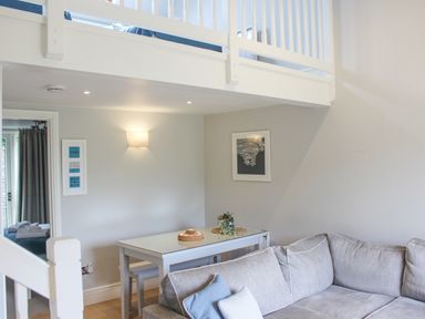 A dining table with benches next to a gray sofa in a living area at 5 Keeper's Cottage Hillfield Dartmouth