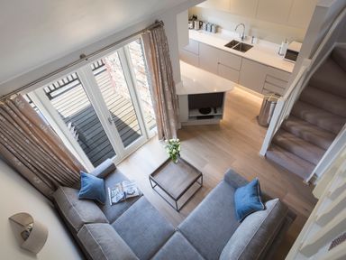 A living room with a sectional sofa and a coffee table next to a kitchen and stairs at 5 Keeper's Cottage Hillfield in Dartmouth