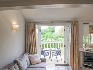 A living room with a sofa and a door opening to a patio with a table and chairs at 5 Keeper's Cottage Hillfield in Dartmouth