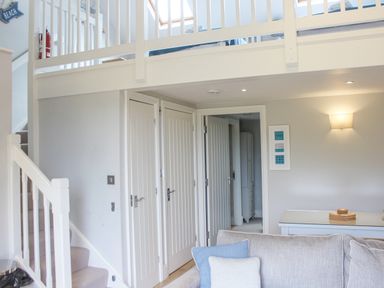 A living room area with a staircase leading to a loft bed and three white paneled doors at 5 Keeper's Cottage Hillfield in Dartmouth