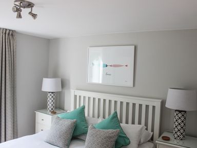 A bedroom with a white bed frame two bedside tables with lamps and a framed picture above the bed at 5 Keeper's Cottage Hillfield Dartmouth
