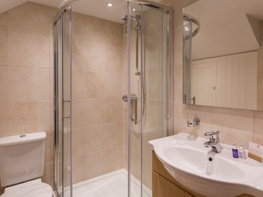 A bathroom with a shower enclosure a toilet and a sink with toiletries at 5 Keeper's Cottage Hillfield Dartmouth