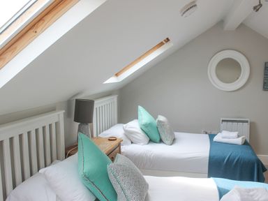 A bedroom with two single beds and turquoise pillows under skylight windows at 5 Keeper's Cottage Hillfield Dartmouth