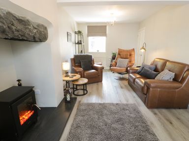 A living room with leather chairs a sofa a fireplace and a carpet at Minffordd in Trawsfynydd