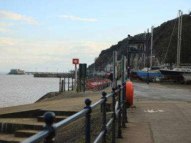A waterfront walkway with bicycles and boats moored on the side at The Headlands - Gower in The Mumbles