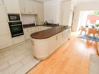 A kitchen with a central island and built-in oven next to a dining area with a table and chairs at The Headlands - Gower in The Mumbles