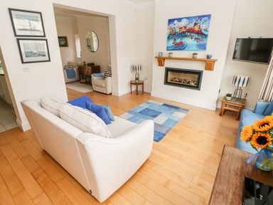 A living room with two sofas a fireplace and a colorful painting at The Headlands - Gower in The Mumbles