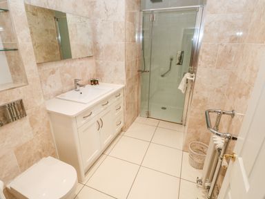 A bathroom with a shower cubicle a sink with cabinet a toilet and a radiator at The Headlands - Gower in The Mumbles