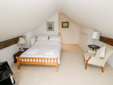 A bedroom with a bed a chair two lamps and framed pictures on the wall at The Headlands - Gower in The Mumbles