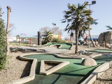 An outdoor mini golf course with palm trees and themed decorations at Number 8 Lakes View in Brean