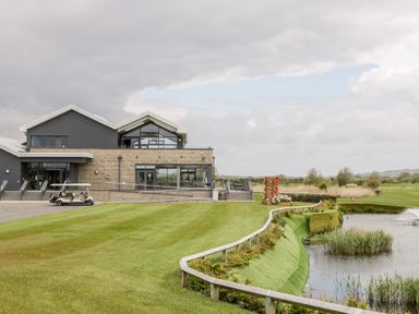 A golf course building next to a pond with a golf cart parked outside at Number 8 Lakes View in Brean