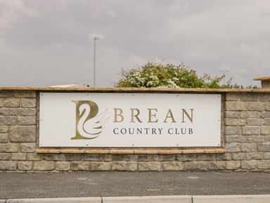 A brick wall with a sign that reads Brean Country Club with a swan logo at Brean