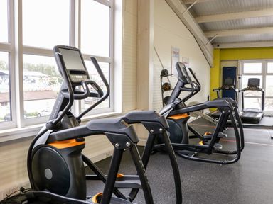 A gym room with elliptical machines and treadmills near windows at Number 8 Lakes View in Brean