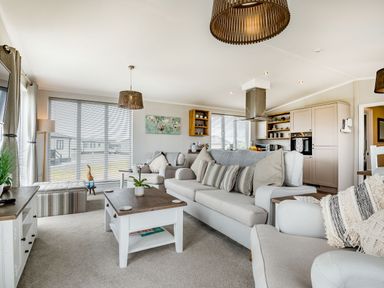 A living room with sofas a coffee table television and windows with blinds at Number 8 Lakes View in Brean