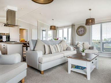 A living room with sofas and a coffee table next to a kitchen area at Number 8 Lakes View in Brean