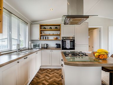A kitchen with white cabinets a gas stove a sink toaster kettle and fruit bowl at Number 8 Lakes View in Brean