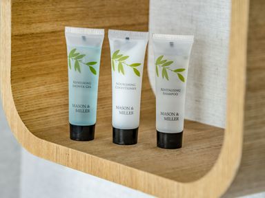 Three small tubes of Mason and Miller toiletries on a wooden shelf