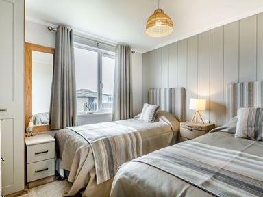 A bedroom with two single beds striped bedding bedside tables and a window with curtains at Number 8 Lakes View in Brean