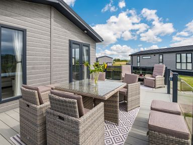 An outdoor patio with wicker chairs and a table with a vase of flowers at Number 8 Lakes View in Brean