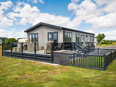 A modern single story house with a glass fenced patio and outdoor wicker furniture at Number 8 Lakes View in Brean