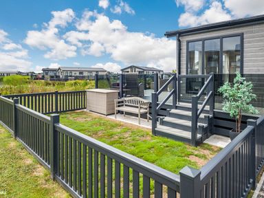 A small fenced garden area with a bench and planter next to a deck with stairs and glass doors at Number 8 Lakes View in Brean