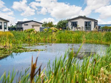 A pond with ducks and water lilies in front of two houses with decks at Number 8 Lakes View in Brean