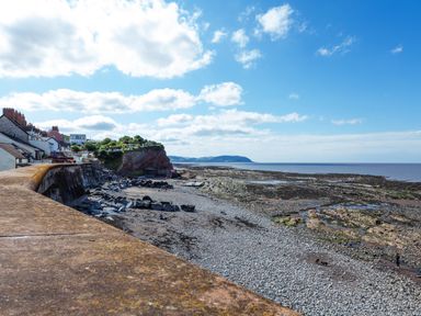 A pebble beach with a stone sea wall and houses along the coast at Sea Spray Watchet