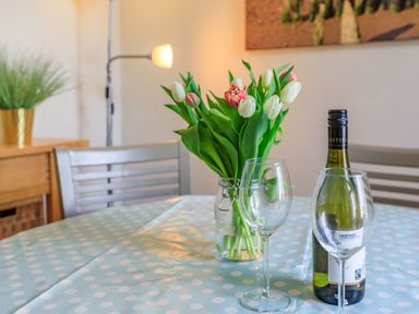 A dining table with a vase of tulips white wine bottle and two wine glasses at Sea Spray in Watchet