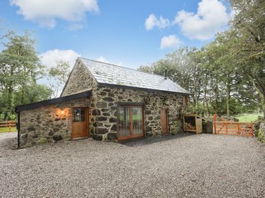 A stone house with wooden doors and a gravel driveway at Yr Hen Oriel in Llanrug