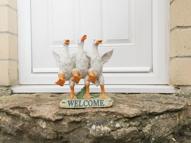 A welcome decoration with three white ducks in front of a white door at Orchard House Cottage in Malmesbury