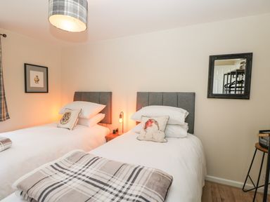A bedroom with two single beds with grey headboards and bird cushions at Orchard House Cottage in Malmesbury