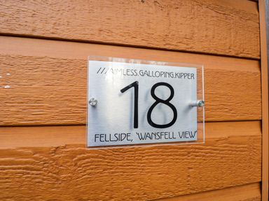 Metal house number sign 18 mounted on wooden exterior wall at Wansfell View in Limefitt Park near Troutbeck