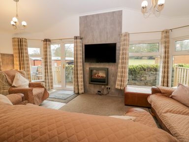 A living room with couches armchair wall-mounted TV and fireplace at Wansfell View Limefitt Park near Troutbeck