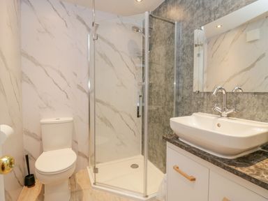 A bathroom with a toilet shower enclosure and sink on a countertop at Wansfell View Limefitt Park near Troutbeck