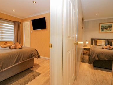 Two bedrooms with beds towels on beds wall mounted television and bedside lamp at Wansfell View Limefitt Park near Troutbeck