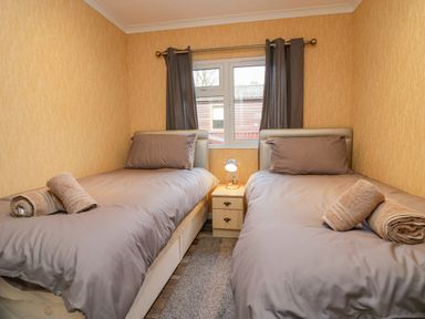 A bedroom with two single beds with gray bedding and towels on each bed at Wansfell View in Limefitt Park near Troutbeck