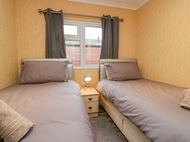 A bedroom with two single beds a nightstand and a window at Wansfell View in Limefitt Park near Troutbeck