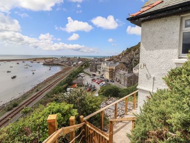 A coastal view with a railway track and houses near the shore at Windycroft in Barmouth