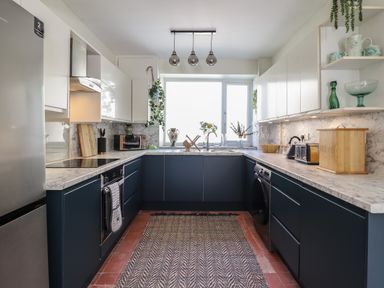 A kitchen with marble countertops and dark blue lower cabinets at Windycroft in Barmouth