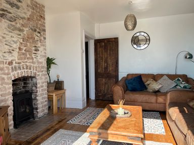 A living room with a stone fireplace brown leather sofas a wooden coffee table and a wall clock at Windycroft in Barmouth