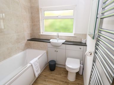 A bathroom with a bathtub a sink toilet and a chrome towel radiator at Chalfonts Cottage in Trefin near Penparc