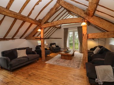 A living room with wooden beams dark sofas coffee table and rug at 1 White House Cottages Bromsash near Lea