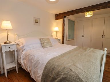 A bedroom with a double bed two bedside tables with lamps a large mirror and built-in wardrobes at 1 White House Cottages Bromsash near Lea