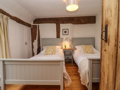 A bedroom with two single beds and wooden beams at 1 White House Cottages Bromsash near Lea