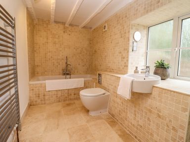 A bathroom with a bathtub toilet sink and towel near a window at 1 White House Cottages Bromsash near Lea