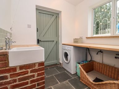 A utility room with a sink washing machine wicker basket and wooden countertop at 1 White House Cottages in Bromsash near Lea