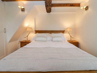 A bedroom with a wooden bed two bedside tables and lamps at 1 White House Cottages Bromsash near Lea
