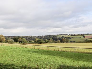 A green field with a wooden fence and trees in the distance at 1 White House Cottages Bromsash near Lea
