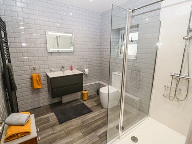 A bathroom with a shower enclosure toilet vanity unit mirror and towels at Y Felin The Granary in Caernarfon