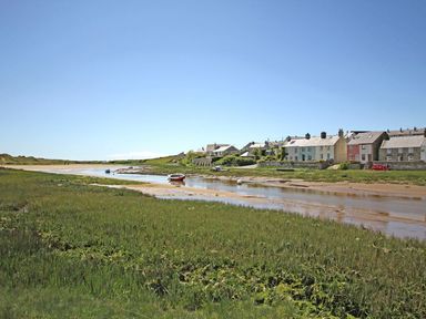 A coastal village with boats on a river and houses along the shore at 7 Bro Branwen Aberffraw near Rhosneigr